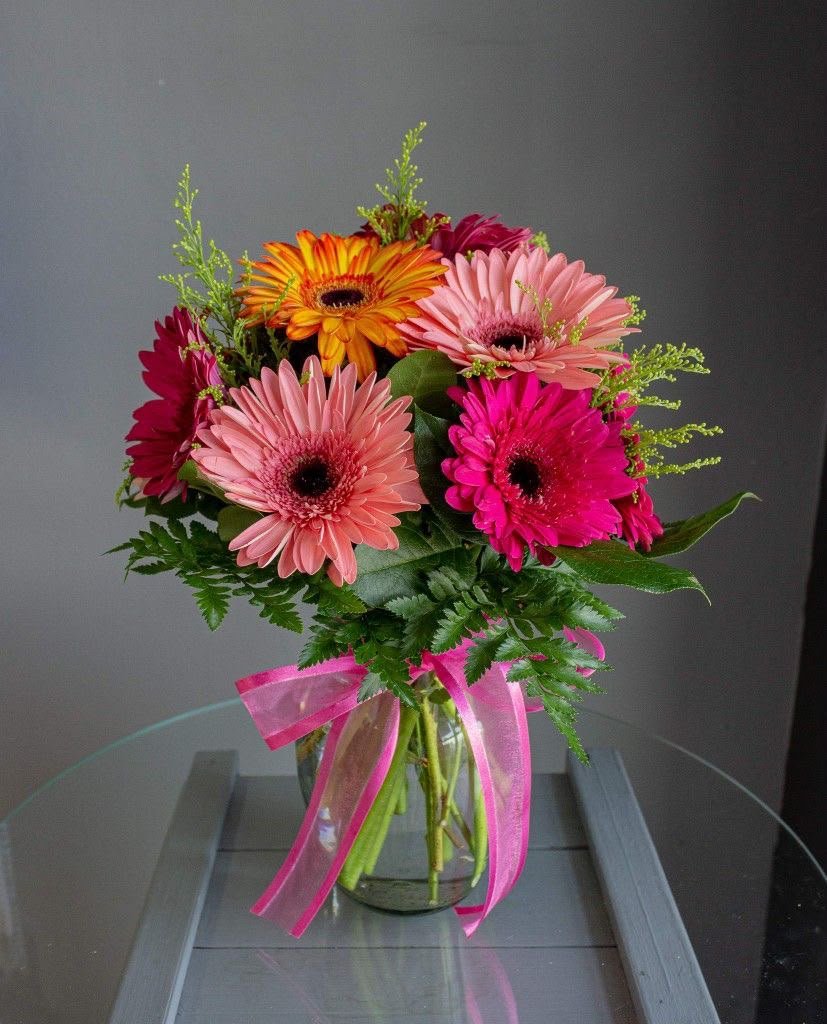Ramo de gerberas de colores con flores rosadas y follaje verde