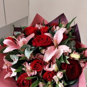 Ramo de rosas rojas y lirios rosados con follaje verde