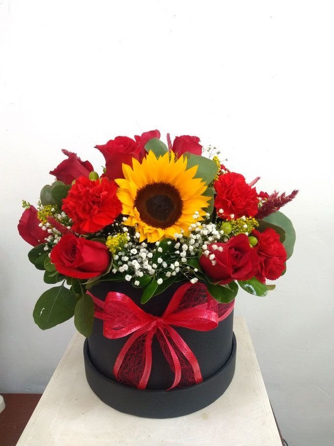 Caja de flores rojas con girasol y rosas